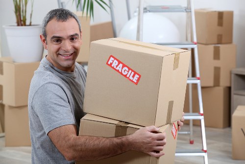 Removal van and movers handling furniture on a residential street in Ickenham